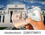 dollars in a man's hand on the background Federal Reserve Building in Washington DC, United States, FED