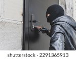 Small photo of Burglar breaking into house. A burglar opens the lock on the iron door of a country house. A criminal concept. Burglary.