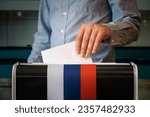 Small photo of male hand of a voter lowers the ballot in the ballot box. concept of state elections. voters to vote on a single voting day in Russia at a polling station