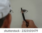 Small photo of Paris, France - 06 24 2023 : A draftsman draws a person's eyes