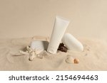 Small photo of Sunscreen in white plastic tube. Studio photo shoot with sand, shells and white stones. Sand-colored environment. Sunscreen with UVA and UVB protection. Summer atmosphere. Landscape format.