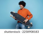 Emotional African American man holding longboard simulate playing guitar, having fun isolated on blue background. Positive emotions