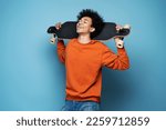 Attractive happy African American man with closed eyes holding longboard isolated on blue background. Active lifestyle concept