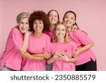 Small photo of Group of smiling confident multiracial women wearing t shirts with pink ribbon looking at camera isolated on pink background. Health care, support, prevention. Breast cancer awareness month concept