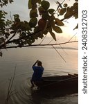 Small photo of Image is silhouette. A fisherman on a wooden boat is catching fish using a trawl around Nusakambangan Island at sunrise. June 19, 2022.