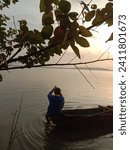 Small photo of Image is silhouette. A fisherman on a wooden boat is catching fish using a trawl around Nusakambangan Island at sunrise. June 19, 2022.