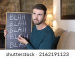 Small photo of Man holding chalkboard with "blah blah blah" hand written