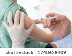 Close up of a Doctor making a vaccination in the shoulder of patient, Flu Vaccination Injection on Arm, coronavirus, covid-19 vaccine disease preparing for human clinical trials vaccination shot.