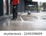 Small photo of cleaning staff hoses a portable car for washing the concrete floor with high-pressure water jets.