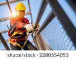 Small photo of A worker working at height equipment. Fall arrestor device for worker with hooks for safety body harness on the roof structure. Safety body construction. selective focus of hook safety body harness.