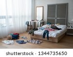 modern bright bedroom with messy clothes scatter on white bed and floor. empty room with nobody in cozy apartment. packing luggage suitcase for summer vacation and spring holidays concept lifestyle.