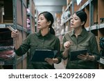 Small photo of two asian young girl colleague in uniform walking together in factory warehouse. manager woman training new employee in storehouse. elegant ladies working in stockroom of famous clothes shop.