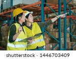 Small photo of two warehouse coworkers women talking in large workplace. group of asian lady employees working in stockroom discuss place to put parcel. manager showing while point to box on shelf to colleague