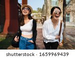 young smiling asian japanese women in sunglasses walking and talking in sunset time outdoor. Happy best friends laughing and having fun while relax in old city street. tourists sightseeing in summer