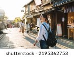 Small photo of backlit photograph asian female backpacker is gazing into the distance with curiosity while walking down historic ninen zaka street at dusk in autumn Kyoto japan