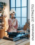 Small photo of vertical shot elegant asian lady wearing nightgown with a towel on head is drinking and tasting wine from glass after shower in the evening by the kitchen window at home