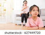 Small photo of young lovely children was bored with her angry mother loudly nag feeling impatient hate annoying when mom was sitting behind her on sofa in living room at home.