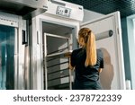 Small photo of Shot from the back of a girl a pastry chef puts candy to harden in the refrigerator and sets the cooling temperature