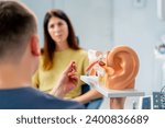 Small photo of an ENT doctor consults a patient in the clinic's office tells about the possible consequences of the operation shows ear and nasal canals