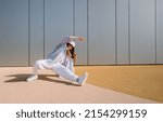 Small photo of Young hip hop girl in oversize outfit wearing dancing into music minimalistic urban background. Hip-hop queen. Breakdancer woman. minimalistic