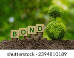 Green bonds concept. Words BOND on a wood block place on coin stack and Green Globe with tree on top. Investment on bonds, Raising funds to fund environmentally friendly projects.green investment.
