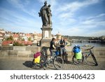 Small photo of Prague,Czech Republic - Sep 16 2015 : Two people traveling by bicycle stop for a drink under the Statue of St. Antonius of Padua on the Charles Bridge in Prague