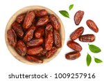dry dates with green leaves in wooden bowl isolated on white background. Top view. Flat lay pattern