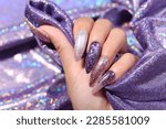 Female hand with silver nail design. Glitter silver nail polish manicure. Model hand with perfect manicure hold white lace fabric on white background.