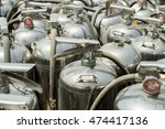 Small photo of Close up of depressurized discarded old silver fire extinguishers standing with others abandoned in the sun.