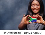 African woman hold small South Africa flag in hands.