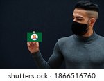 Egyptian man in gray turtleneck and black face protect mask show Beni Suef flag isolated background. Governorates of Egypt coronavirus concept.