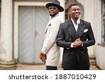 Two fashion black men. Fashionable portrait of african american male models. Wear suit, coat and hat.
