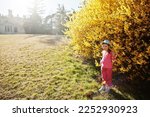Baby girl in cap at near golden bushes at Lednice park, Czech Republic.