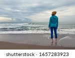 A Girl Stands On A Sandy Beach. ...