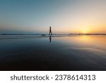 Small photo of silhouette of a woman walking along the seashore. Spiritual Peace Meditation. A happy girl walks along the seashore against the backdrop of sunset. side view.