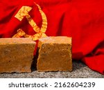 Small photo of The concept of photo of dissolution of the Soviet Union, the Cold War, communism, totalitarianism, decommunization. Cracked brick next to the USSR flag.