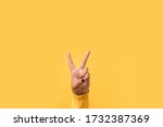 Hand gesture V sign for victory or peace sign over yellow background