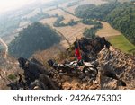 Small photo of NAM XAY VIEWPOINT, VANG VIENG, LAOS - FEBRUARY 16, 2024: Ancient motorcycle parked and Lao flag on the Nam Xay Viewpoint, During the dry season in Laos.
