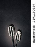 Small photo of Hand mixer beaters with white cream cheese filling against black background. Dark cooking aesthetic. Process of making birthday cheesecake.