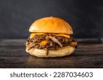 Isolated double cheese smash burger with sweet onions and sauce in a dark background. Hamburger with two patties and salad in wooden table