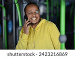 Small photo of a lustful dark-skinned young man is sitting in the bus and talking on the phone