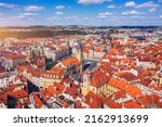 Prague beautiful panoramic sunny aerial drone view above Prague Old Town Square with Church of Our Lady before Tyn and Prague Astronomical Clock Tower. Drone flight over red roofs of Prague, Czechia.