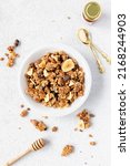 Small photo of Homemade granola in a white bowl on a white background with a spoon, overheadtop view. Homemade whole grain musli with bananas and dark chocolate for breakfast. Light, airy, clean. Breakfast cereal.