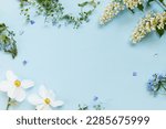 Spring flowers flat lay on blue background. Floral card template with space for text. Happy easter! Mothers day! Daffodils, forget me nots and wildflowers in frame layout