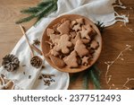 Christmas gingerbread cookies in wooden plate on rustic table flat lay with fir branches, pinecone, spices. Merry Christmas! Delicious fresh gingerbread cookies close up, atmospheric holiday
