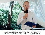 Small photo of stylish handsome emcee performing speech for toast at wedding reception