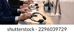 Small photo of Panorama focus hand holding headset on call center workspace desk with blur background of operator team or telesales representative engaging in providing client with customer support service. Prodigy