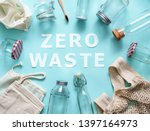 Zero waste concept. Textile eco bags, glass jars and bamboo toothbrush on blue background with Zero Waste white paper text in center. Eco friendly and reuse concept. Top view or flat lay