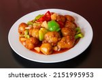 Sweet and sour pork of traditional Cantonese yum-cha Asian gourmet cuisine meal food dish on the white serving plate and brown red table