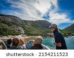 Small photo of Cruising tour with people, guide tour introducing at stone rock mountain forest seascape in the Bass Strait at Wilson Promontory Victoria Australia, blue sky and blue sea